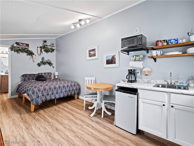 bedroom with refrigerator, light wood-style flooring, baseboards, and a sink