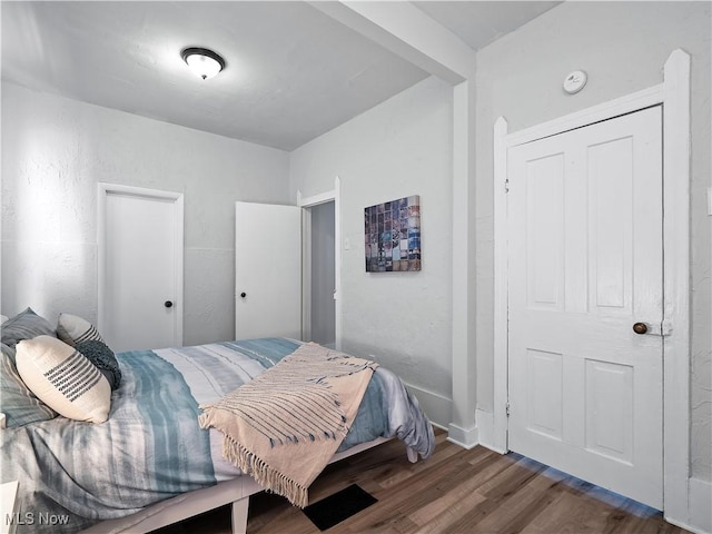 bedroom featuring wood finished floors and a textured wall