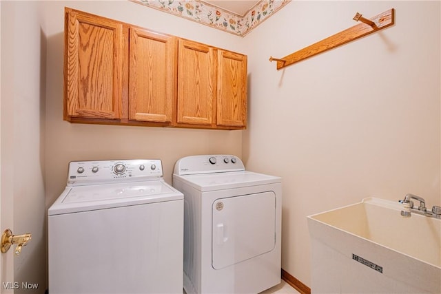 washroom featuring washer and dryer, cabinet space, and a sink