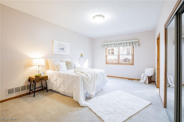 bedroom with visible vents, baseboards, light colored carpet, and a closet