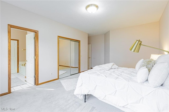 bedroom with a closet, baseboards, ensuite bathroom, and carpet flooring