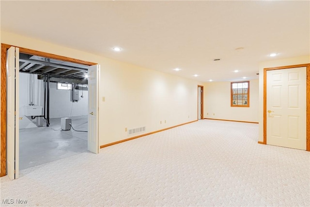 basement with a healthy amount of sunlight, baseboards, visible vents, electric panel, and recessed lighting