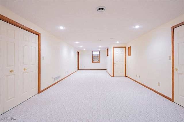 below grade area with visible vents, light colored carpet, and baseboards