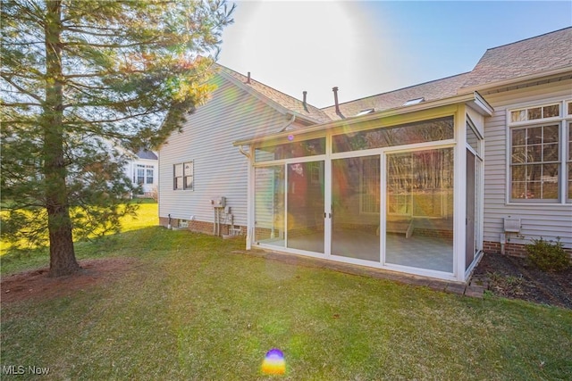 back of house featuring a lawn and a sunroom