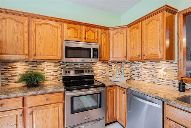 kitchen featuring light stone counters, tasteful backsplash, and stainless steel appliances