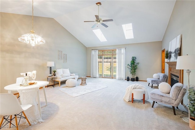 living area featuring ceiling fan, carpet, a fireplace, a skylight, and high vaulted ceiling