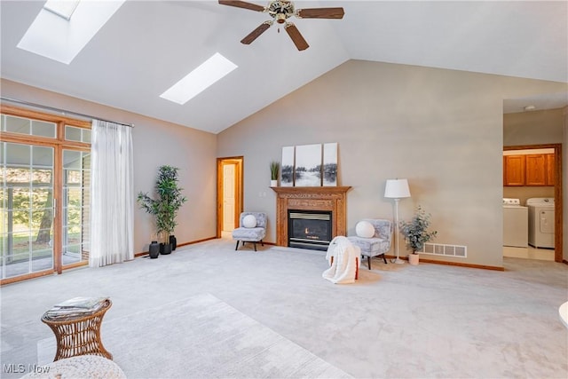 living area with a glass covered fireplace, visible vents, a skylight, and washing machine and clothes dryer