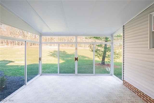 unfurnished sunroom featuring vaulted ceiling and plenty of natural light