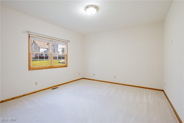 unfurnished room with visible vents, light colored carpet, and baseboards