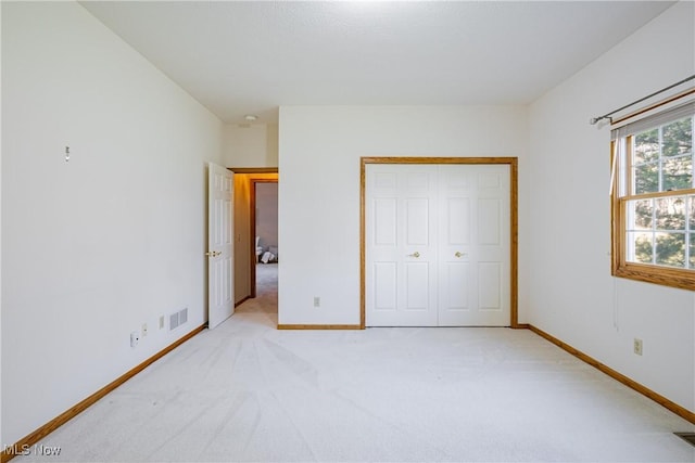 unfurnished bedroom with visible vents, baseboards, light colored carpet, and a closet