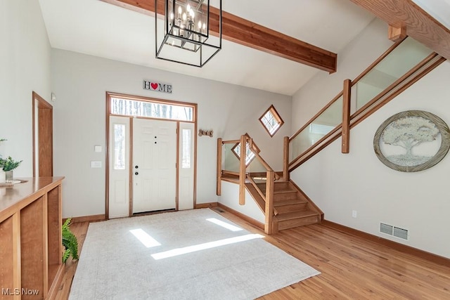 entrance foyer with visible vents, baseboards, stairway, light wood-type flooring, and beam ceiling