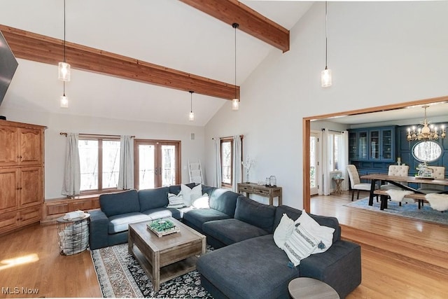 living area featuring beam ceiling, high vaulted ceiling, light wood-style flooring, french doors, and an inviting chandelier