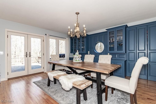 dining room with french doors, light wood-style floors, and an inviting chandelier