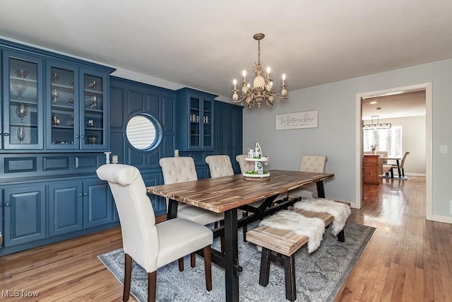 dining area with a chandelier, light wood finished floors, and baseboards