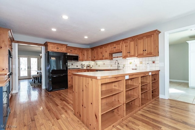 kitchen with stainless steel microwave, freestanding refrigerator, french doors, light wood finished floors, and light countertops