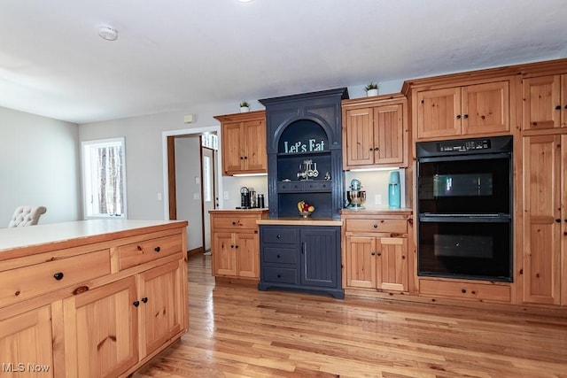 kitchen featuring light countertops, light wood-type flooring, dobule oven black, and open shelves