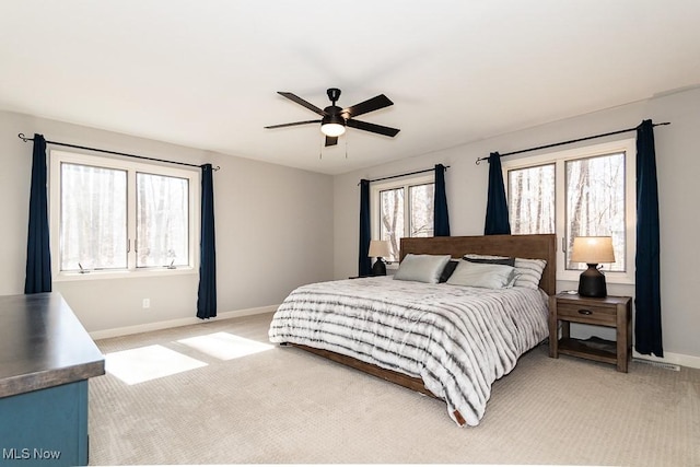 bedroom featuring baseboards, light colored carpet, and a ceiling fan