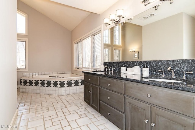 bathroom featuring an inviting chandelier, lofted ceiling, a wealth of natural light, and a sink