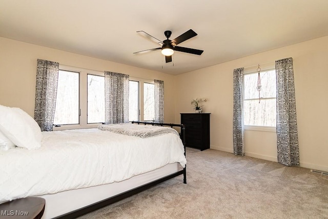 bedroom with multiple windows, light carpet, baseboards, and ceiling fan