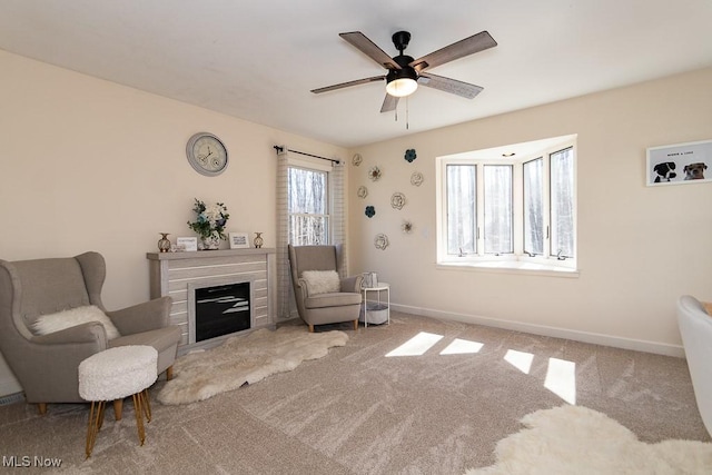 sitting room with a glass covered fireplace, baseboards, carpet floors, and ceiling fan