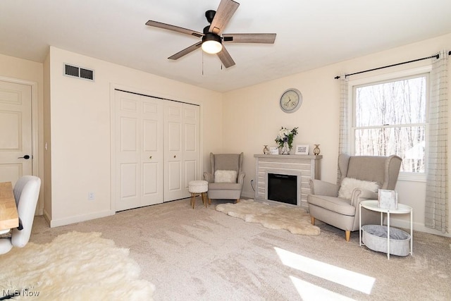 sitting room featuring visible vents, ceiling fan, baseboards, carpet floors, and a fireplace