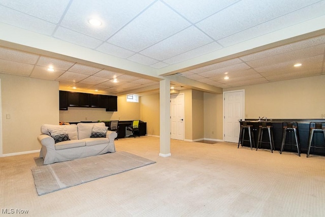 living room featuring light carpet, recessed lighting, a paneled ceiling, baseboards, and indoor bar