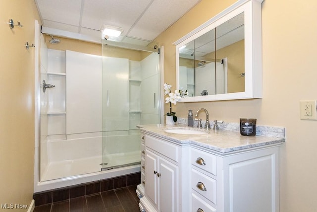 full bathroom featuring a shower stall, vanity, and a paneled ceiling