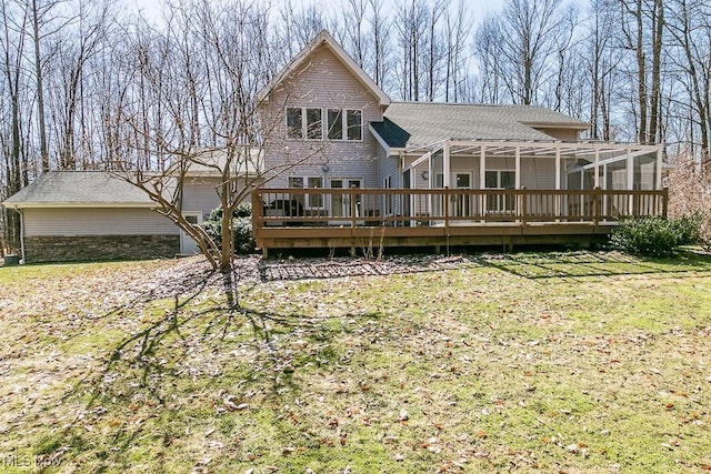 rear view of house with a deck, a shingled roof, and a yard