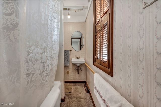 full bath featuring wallpapered walls, baseboards, shower / tub combo with curtain, and a sink