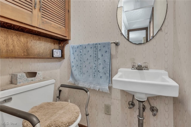 half bath with toilet and wallpapered walls