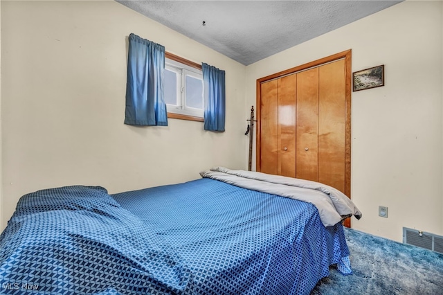 carpeted bedroom featuring a closet, a textured ceiling, and visible vents