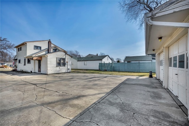 view of side of property featuring concrete driveway and fence