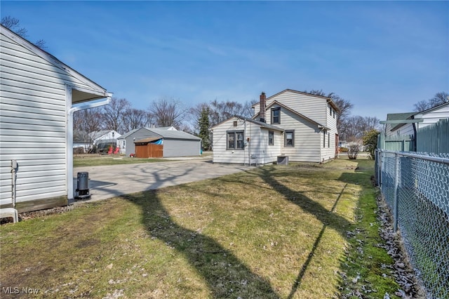 view of side of property with a lawn, a chimney, and fence