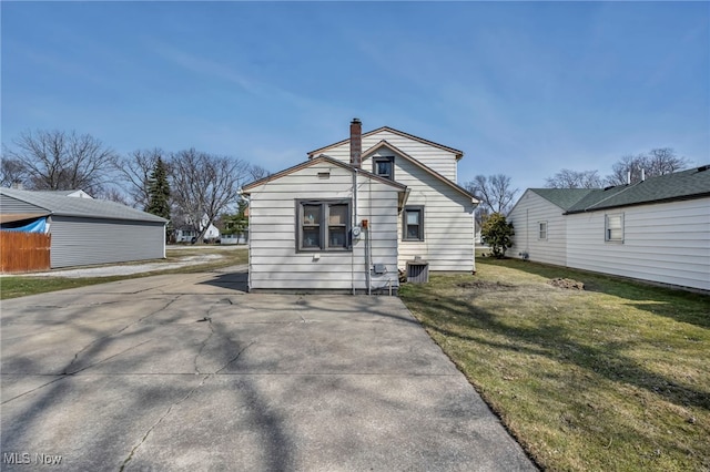 rear view of property with cooling unit, a yard, a chimney, and fence