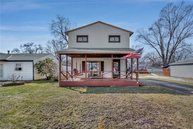 rear view of property with covered porch and a yard