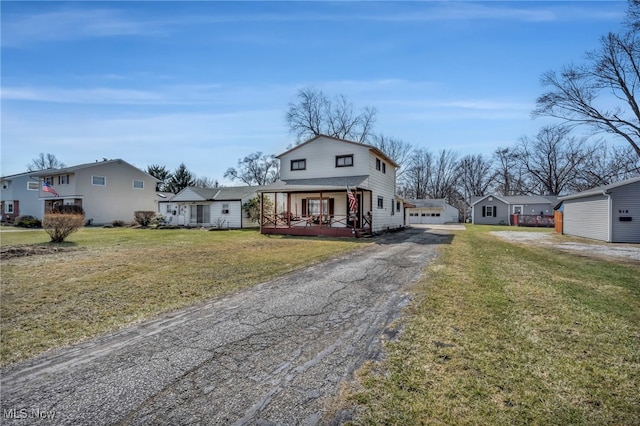 traditional-style home with aphalt driveway, a residential view, covered porch, and a front yard