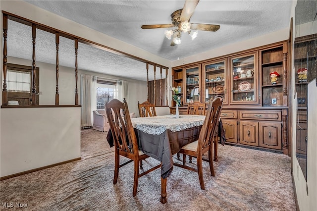 carpeted dining area with a textured ceiling, baseboards, and ceiling fan