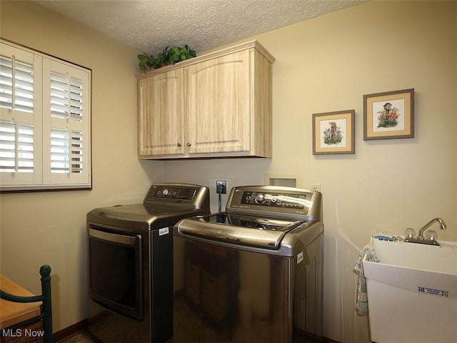 clothes washing area featuring a sink, a textured ceiling, cabinet space, and washer and clothes dryer