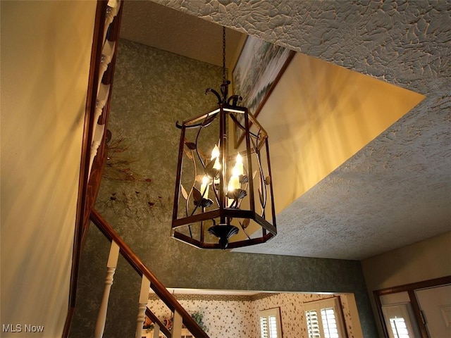 interior details featuring a notable chandelier and wallpapered walls