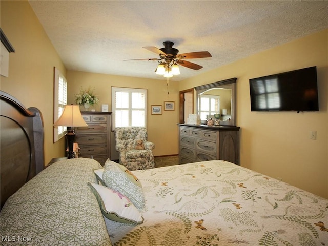 bedroom with ceiling fan, multiple windows, and a textured ceiling