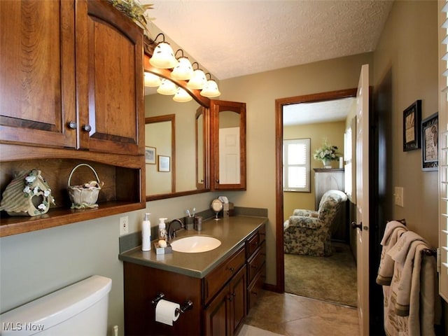 bathroom featuring tile patterned flooring, toilet, a textured ceiling, and vanity