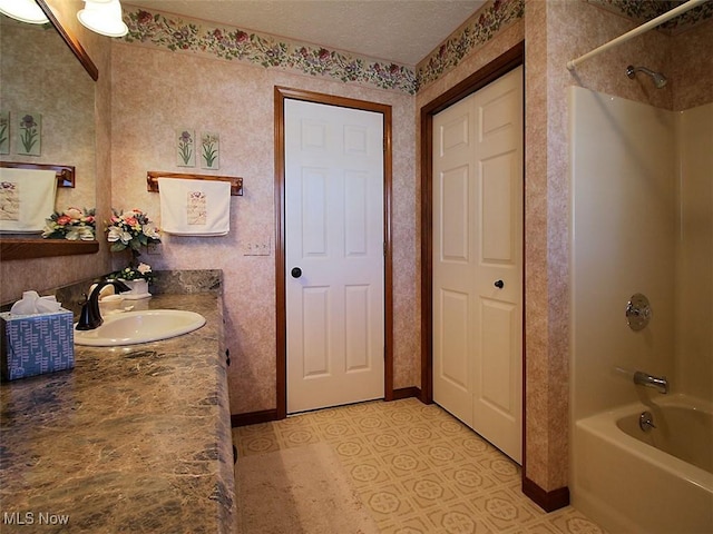 bathroom featuring vanity, a textured ceiling, baseboards, shower / washtub combination, and tile patterned floors