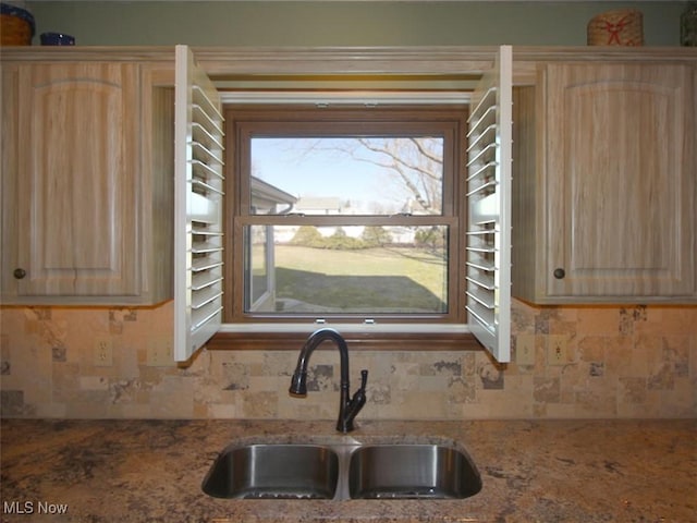 kitchen featuring tasteful backsplash, light brown cabinets, and a sink