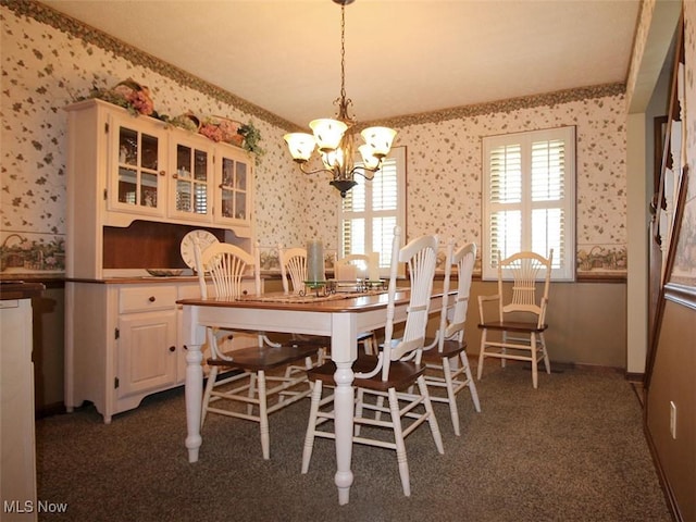 dining space featuring baseboards, a notable chandelier, dark carpet, and wallpapered walls