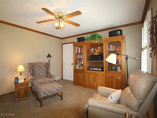 carpeted living room featuring a ceiling fan, visible vents, baseboards, ornamental molding, and a textured ceiling