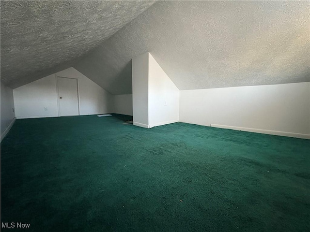 additional living space with vaulted ceiling, baseboards, dark colored carpet, and a textured ceiling