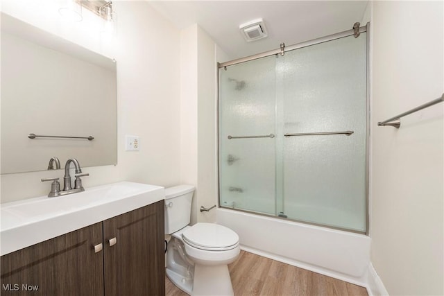 full bath with vanity, toilet, wood finished floors, and combined bath / shower with glass door