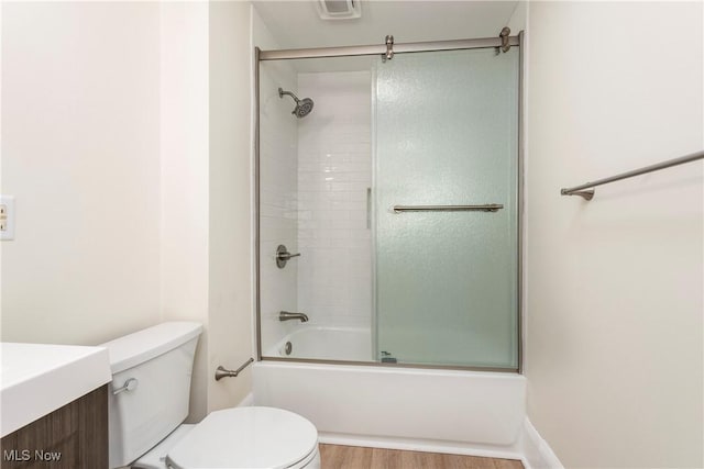 full bath featuring vanity, toilet, wood finished floors, and shower / bath combination with glass door