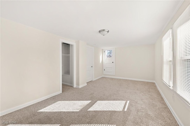 unfurnished room featuring light colored carpet and baseboards