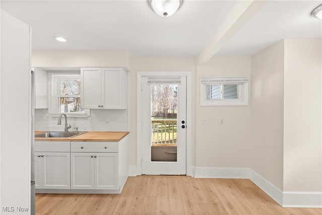 doorway to outside featuring light wood finished floors, recessed lighting, baseboards, and a sink